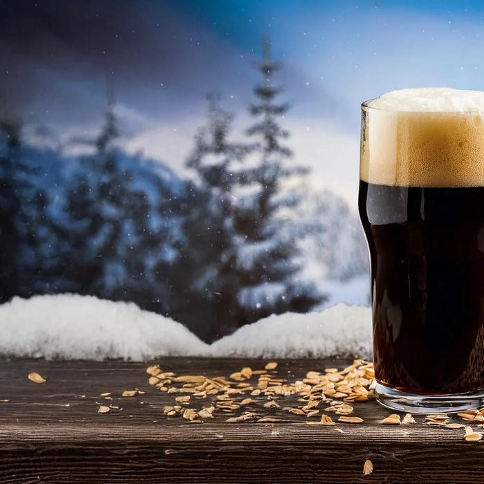 Milk Stout Beer in a Pint Glass with a winter wonderland in the background.