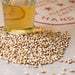 Close up image of Admiral's Feldblume malted grain and a pint glass of wort made with the barley grain to depict the color of the grain.