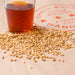 Close up image of Admiral's Hearth malted grain and a pint glass of wort made with the barley grain to depict the color of the grain.