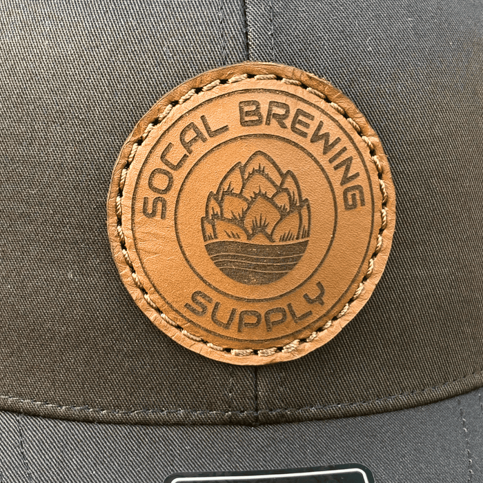 SoCal Brewing Supply Hat with Leather Laser Engraved Logo, the hat is all black in color, close up view.