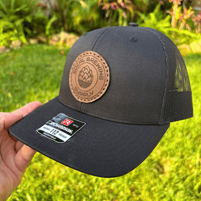 SoCal Brewing Supply Hat with Leather Laser Engraved Logo, the hat is all black in color, side angle view.