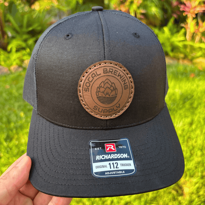 SoCal Brewing Supply Hat with Leather Laser Engraved Logo, the hat is all black in color, head on view.